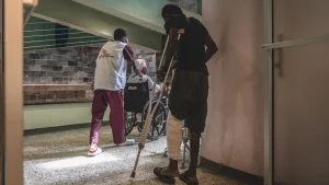 Un miembro del equipo de MSF acompaña a un paciente en el centro de urgencias de Turgeau, Puerto Príncipe, donde se atiende y estabiliza a víctimas de violencia. Haití, junio de 2022.