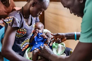 Personal médico vacuna contra la malaria a Yar Mayak, de 3 meses, en brazos de su madre, Ajok Mayak, de 22 años.