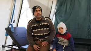 Ali Al Farra sentado junto a su hijo Mohammad Ali al Fara, de 3 años.