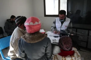 Mohammed Gobasi, trabajador médico de MSF, proporciona una receta a un padre con sus dos hijos en las clínicas móviles de MSF en Guta Oriental. © Omar Haj Kadour