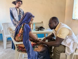 Una médica de MSF examina a Sameera Abkir en la clínica móvil Romalia, en Darfur Occidental. Desarrolló una infección en el brazo debido a una inyección mal administrada tras un parto en casa. Sudán, enero de 2025.
