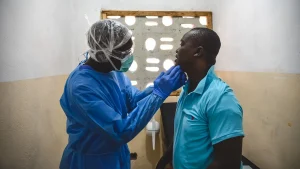 George Kamara, oficial de salud comunitaria de MSF, examina a un paciente dentro del centro de tratamiento mpox en la ciudad de Calaba, Freetown, Sierra Leona, junio de 2025.