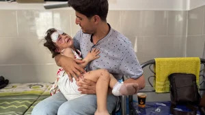 Julia, de 4 años, es sostenida por su padre Ahmed después de resultar herida en un ataque aéreo en su casa en la ciudad de Gaza.