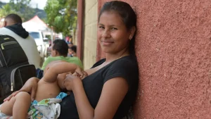 La hija mayor de la familia Brito amamantando a su hijo mientras espera que su familia reciba consulta médica.