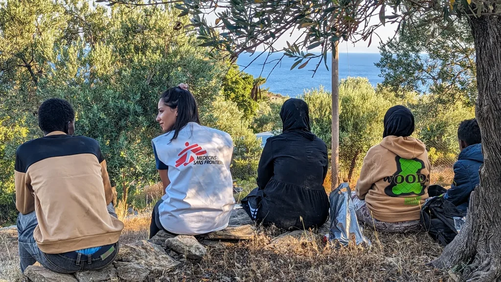 Un miembro del equipo de MSF se sienta con un grupo de recién llegados a Lesbos, quienes descansan tras recibir asistencia de nuestros equipos y agua y comida.