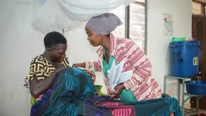 Una enfermera auxiliar de MSF y una madre atienden a un bebé en la sala de maternidad del hospital de MSF en el campo de Nduta.