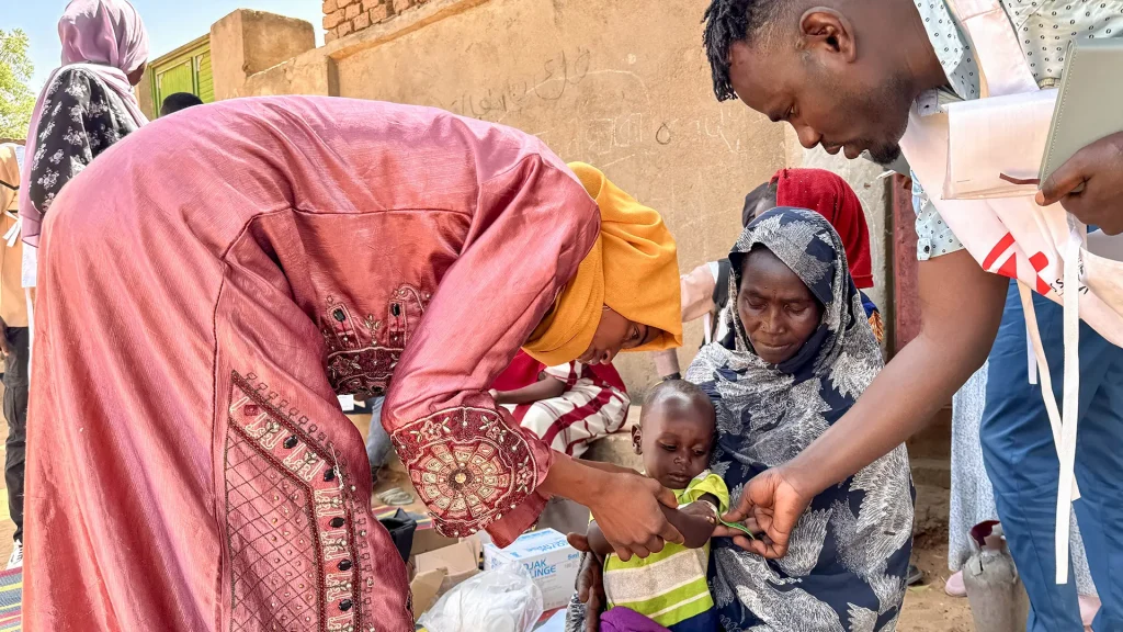 Un voluntario comunitario y un miembro del personal de MSF realizan un cribado MUAC, en Mohamed Ayoub, de 18 meses, inmediatamente después de su vacunación contra el sarampión.