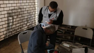 Un médico de MSF utiliza la luz de su teléfono móvil durante una consulta con un paciente en una clínica móvil ubicada en un albergue para desplazados. Beirut, Líbano, marzo de 2026.