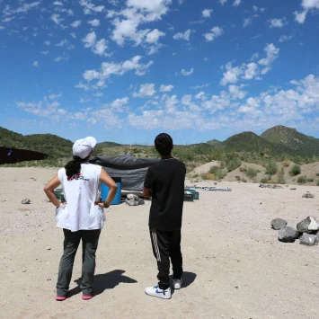 La coordinadora del proyecto, Belén Ramírez, y un chico de 17 años de Bangladesh observan un helicóptero que sobrevuela el campamento de End of the Wall.