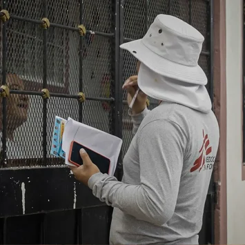David, promotor de salud de MSF, conversa con una vecina de la comunidad para informarle sobre la liberación de mosquitos con Wolbachia que MSF planea realizar en esta zona de Tegucigalpa.