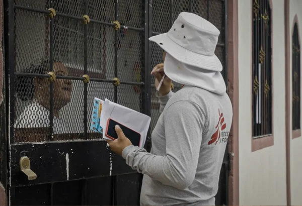 David, promotor de salud de MSF, conversa con una vecina de la comunidad para informarle sobre la liberación de mosquitos con Wolbachia que MSF planea realizar en esta zona de Tegucigalpa.