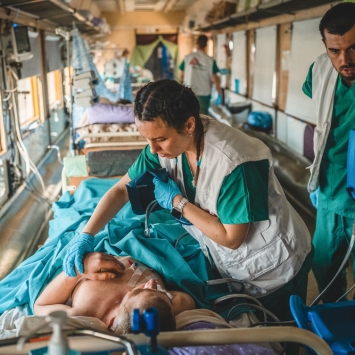 El equipo a bordo del tren medicalizado de MSF en Ucrania estabilizando a un paciente severamente herido de guerra. Desde el 31 de marzo, hemos trasladado a al menos 600 pacientes. © Andrii Ovod