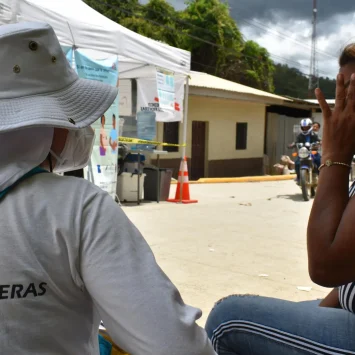 Una de las promotoras de salud escucha la plática de la familia Brito sobre cómo fue su experiencia por el Darién.