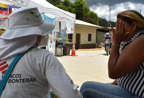 Una de las promotoras de salud escucha la plática de la familia Brito sobre cómo fue su experiencia por el Darién.