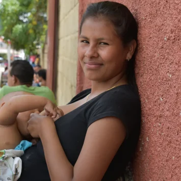 La hija mayor de la familia Brito amamantando a su hijo mientras espera que su familia reciba consulta médica.