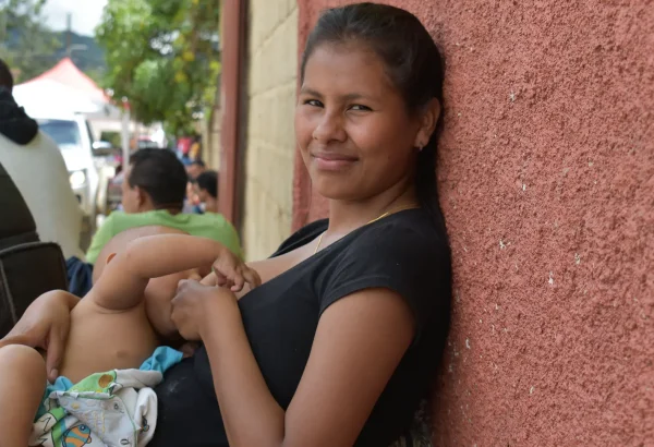 La hija mayor de la familia Brito amamantando a su hijo mientras espera que su familia reciba consulta médica.