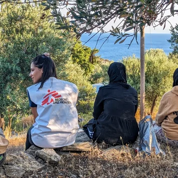 Un miembro del equipo de MSF se sienta con un grupo de recién llegados a Lesbos, quienes descansan tras recibir asistencia de nuestros equipos y agua y comida.