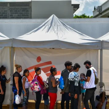 Personas migrantes hacen una fila para acceder a atención médica o acompañamiento psicológico en la clínica móvil de MSF en Danlí.