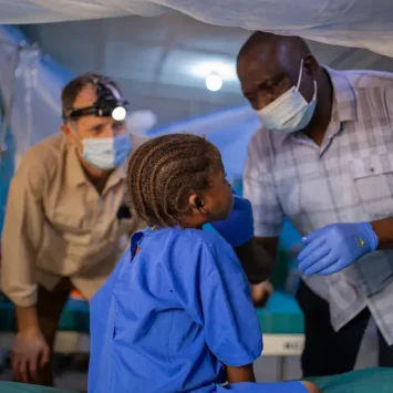El Dr. Kefas y el Dr. Dave examinan a una niña con noma (ETD) que se sometió a una cirugía reconstructiva que le cambió la vida. Nigeria, octubre de 2023.