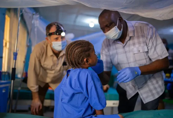 El Dr. Kefas y el Dr. Dave examinan a una niña con noma (ETD) que se sometió a una cirugía reconstructiva que le cambió la vida. Nigeria, octubre de 2023.