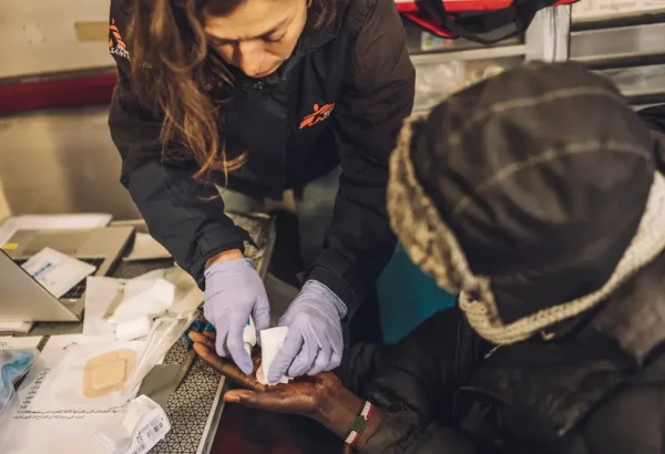 Personal de Médicos Sin Fronteras hace curación en la mano de un migrante menor no acompañado