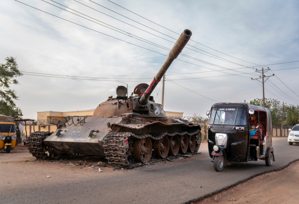 Un taxi rickshaw rodea un tanque destruido de las Fuerzas Armadas sudanesas.