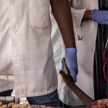 Una enfermera sostiene la mano de Haidara Atim, de 10 años, que sufría de bronquitis traqueal y shock séptico, después de que muriera cuando los médicos no pudieron resucitarlo en la unidad de cuidados intensivos del Hospital MSF en Metche, en el este de Chad, el 7 de agosto de 2024.