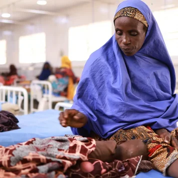 Asma'u se sienta junto a su hija, Shamsiya, quien ha sido ingresada en el centro de alimentación terapéutica para pacientes hospitalizados Kofar Suari por desnutrición, en el estado de Katsina, Nigeria, en octubre de 2024.