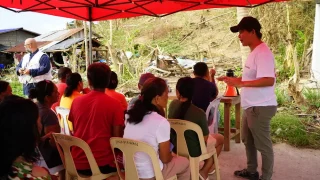Sarah Jane Deocampo, responsable de salud mental, realiza una sesión de psicoeducación mientras los pacientes esperan su turno en la clínica móvil. Filipinas, 2024.