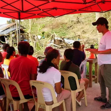 Sarah Jane Deocampo, responsable de salud mental, realiza una sesión de psicoeducación mientras los pacientes esperan su turno en la clínica móvil. Filipinas, 2024.