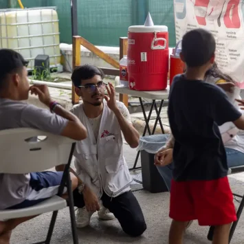 Trabajador de MSF conversa con dos niños en el albergue Pumarejo, en Matamoros, México, donde brindamos atención a personas migrantes.