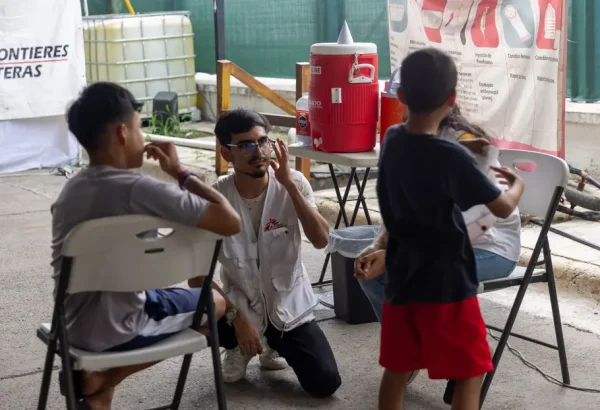 Trabajador de MSF conversa con dos niños en el albergue Pumarejo, en Matamoros, México, donde brindamos atención a personas migrantes.