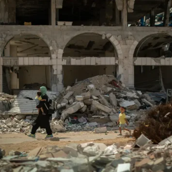 una mujer lleva a su hijo de vuelta a casa entre los escombros. Gaza, Palestina.