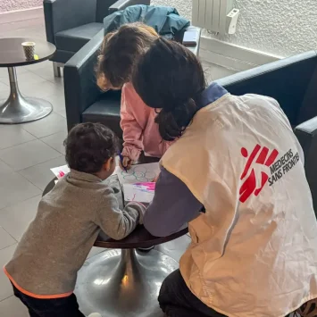 Dos niños iraníes con su madre en Calais. MSF les dio cobijo. Aquí juegan con una trabajadora de MSF. © Mohammad Ghannam / MSF