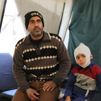 Ali Al Farra sentado junto a su hijo Mohammad Ali al Fara, de 3 años.