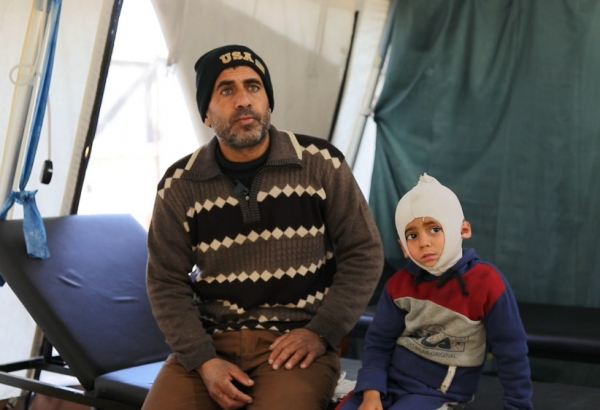 Ali Al Farra sentado junto a su hijo Mohammad Ali al Fara, de 3 años.