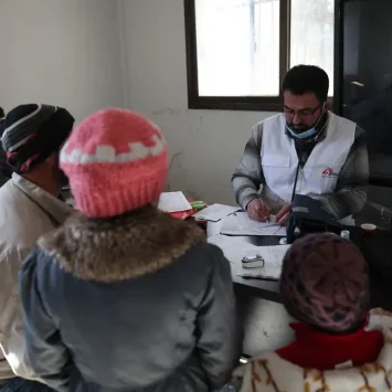 Mohammed Gobasi, trabajador médico de MSF, proporciona una receta a un padre con sus dos hijos en las clínicas móviles de MSF en Guta Oriental. © Omar Haj Kadour