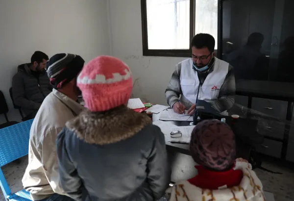 Mohammed Gobasi, trabajador médico de MSF, proporciona una receta a un padre con sus dos hijos en las clínicas móviles de MSF en Guta Oriental. © Omar Haj Kadour