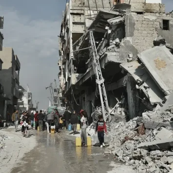 La gente recoge agua junto a un edificio que está en peligro de derrumbarse en Beit Lahia, en el norte de Gaza.