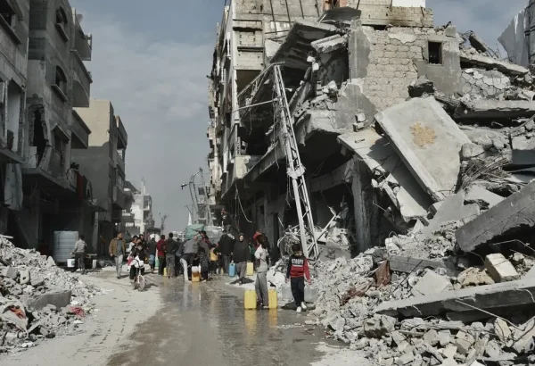 La gente recoge agua junto a un edificio que está en peligro de derrumbarse en Beit Lahia, en el norte de Gaza.