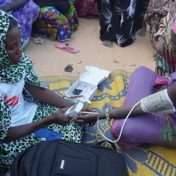Una partera de MSF toma la presión arterial de una mujer embarazada en un campo para personas desplazadas internas en Ansongo, Mali.