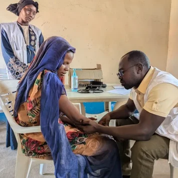 Una médica de MSF examina a Sameera Abkir en la clínica móvil Romalia, en Darfur Occidental. Desarrolló una infección en el brazo debido a una inyección mal administrada tras un parto en casa. Sudán, enero de 2025.
