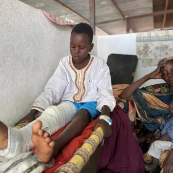 Adil se incorpora en la cama del pabellón pediátrico del hospital de Tawila, mientras su madre, Nawal, y su hermano, Musa, se sientan a su lado.