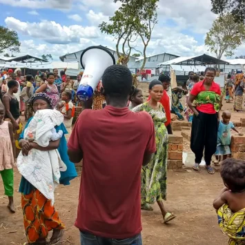 Con un megáfono en la mano, un activista comunitario de MSF recorre el campo de Musenyi para animar a los padres a vacunar a sus hijos contra el sarampión.