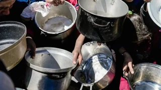 Niños y niñas sostienen sus ollas vacías en una cocina comunitaria en el norte de Gaza, Palestina, febrero de 2025.