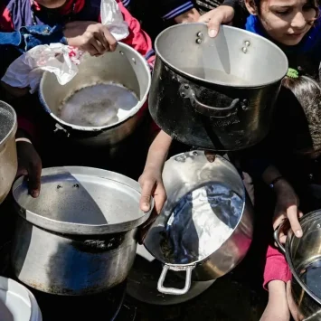 Niños y niñas sostienen sus ollas vacías en una cocina comunitaria en el norte de Gaza, Palestina, febrero de 2025.
