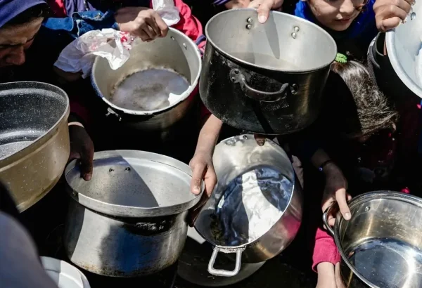 Niños y niñas sostienen sus ollas vacías en una cocina comunitaria en el norte de Gaza, Palestina, febrero de 2025.