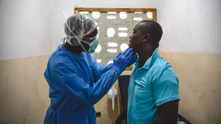 George Kamara, oficial de salud comunitaria de MSF, examina a un paciente dentro del centro de tratamiento mpox en la ciudad de Calaba, Freetown, Sierra Leona, junio de 2025.