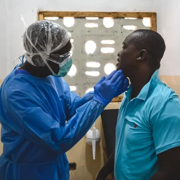 George Kamara, oficial de salud comunitaria de MSF, examina a un paciente dentro del centro de tratamiento mpox en la ciudad de Calaba, Freetown, Sierra Leona, junio de 2025.