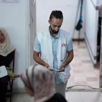 Un miembro del personal de MSF organiza a los pacientes para que vean al personal médico en la clínica de MSF en la ciudad de Gaza, en el norte de Gaza, Palestina, junio de 2025.